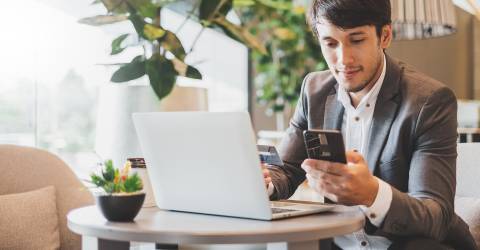 Zakenman met laptop, telefoon en betaalpas doet betaling online